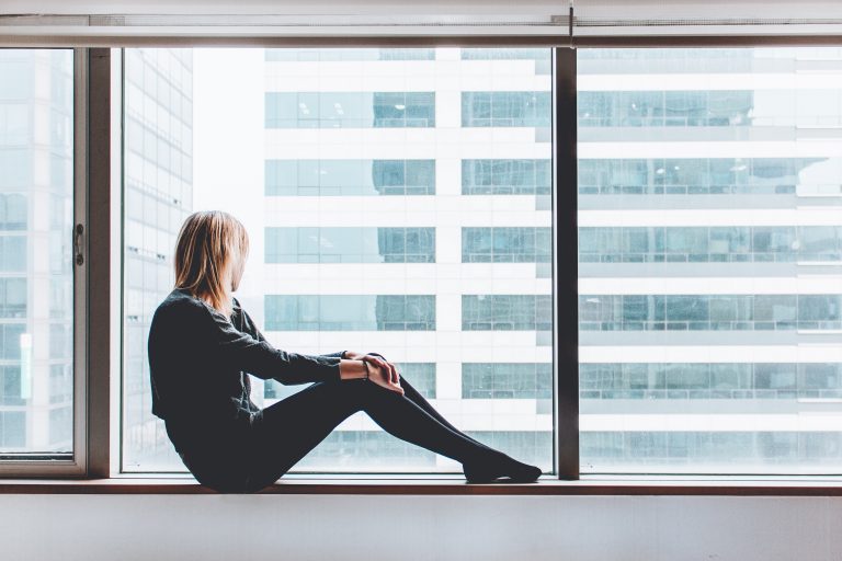 Woman sitting on window sill looking out