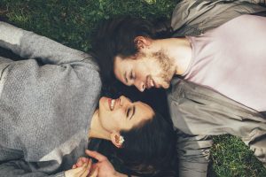 Couple lying on ground facing each other